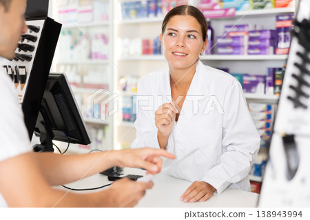 Young female pharmacist serving client buying medicament in drugstore 138943994