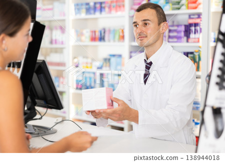 Man pharmacist near cash register area serves customer, scans product and selling drugs Man pharmacist near cash register area serves customer, scans product and selling drugs 138944018