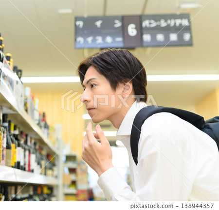 A supermarket where male customers choose wine. A supermarket where male customers choose wine. 138944357