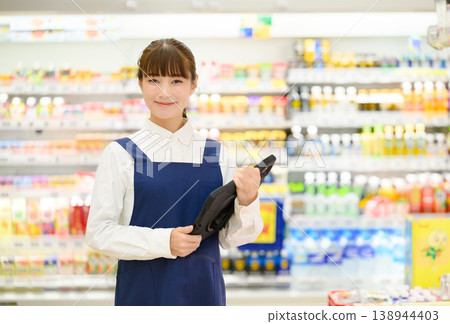 A female store clerk with a smile holding a tablet. 138944403