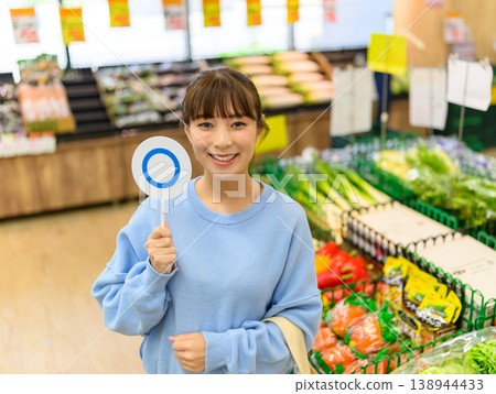 A woman gives an OK sign at the supermarket. A woman gives an OK sign at the supermarket. 138944433