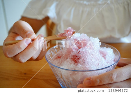 A hand scooping strawberry shaved ice with a spoon: a refreshing summer eating scene. A hand scooping strawberry shaved ice with a spoon: a refreshing summer eating scene. 138944572