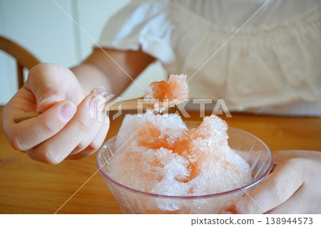 A hand scooping strawberry shaved ice with a spoon: a refreshing summer eating scene. A hand scooping strawberry shaved ice with a spoon: a refreshing summer eating scene. 138944573