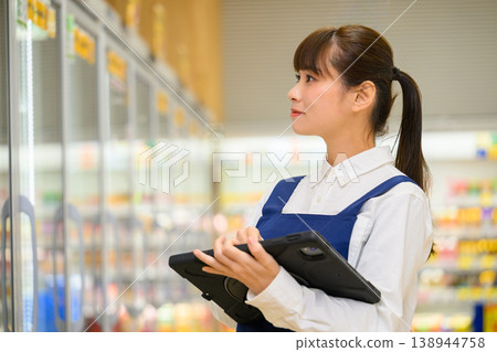 A female store clerk at the supermarket holding a tablet A female store clerk at the supermarket holding a tablet 138944758