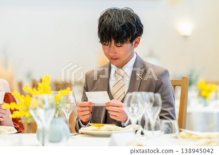 婚禮宴會桌上，一位男賓客正在查看他的座位卡。 138945042
