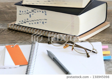 A learning environment with a dictionary, notebook, and glasses. A learning environment with a dictionary, notebook, and glasses. 138945098