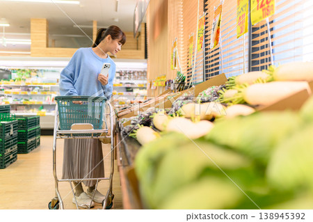 A woman choosing vegetables at a supermarket. 138945392
