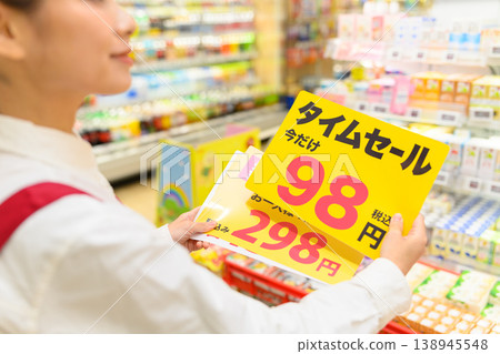 A female store clerk checking sale information at the supermarket. A female store clerk checking sale information at the supermarket. 138945548