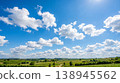 A summer countryside landscape with blue skies and white clouds, green hills and a single road—a peaceful rural panorama. 138945562