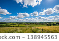 A panoramic view of the English countryside with a summer blue sky and white clouds, a village with a wheat field in bloom and a church. 138945563