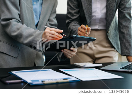 Business documents on office table with smart phone and calculator digital tablet and graph business with social network diagram and two colleagues discussing data Business documents on office table with smart phone and calculator digital tablet and graph business with social network diagram and two colleagues discussing data 138945656