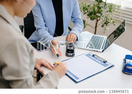 Car insurance contract signing with financial advisor. Customer reviewing agreement with car model on desk, representing auto insurance, finance, loan Car insurance contract signing with financial advisor. Customer reviewing agreement with car model on desk, representing auto insurance, finance, loan 138945671