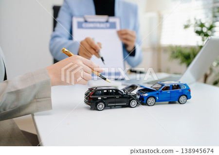 Car insurance contract signing with financial advisor. Customer reviewing agreement with car model on desk, representing auto insurance, finance, loan Car insurance contract signing with financial advisor. Customer reviewing agreement with car model on desk, representing auto insurance, finance, loan 138945674