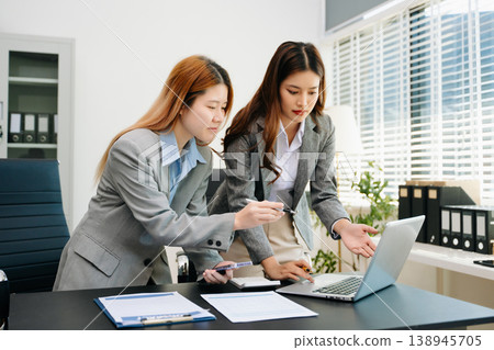 Businesswomen work and discuss their business plans. A Human employee explains and shows her colleague the results paper 138945705