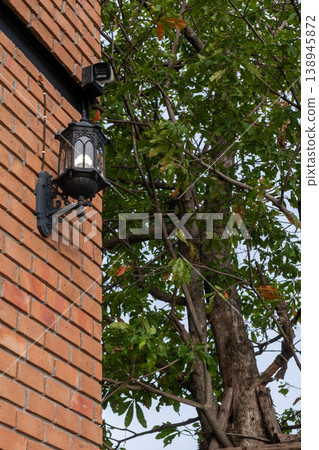 A modern brick building, with window and wall lamps. with tree on the background 138945872