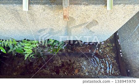 A beautiful, tranquil Japanese scene unfolds, with clear water flowing from a stone basin, surrounded by moss and grass. A beautiful, tranquil Japanese scene unfolds, with clear water flowing from a stone basin, surrounded by moss and grass. 138945970