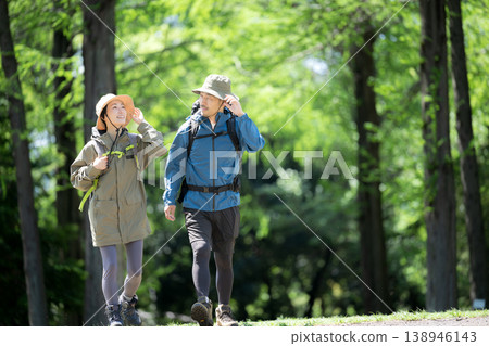 一張情侶漫步在鬱鬱蔥蔥的春日森林中的全身照,他們正在進行徒步旅行等戶外活動。 一張情侶漫步在鬱鬱蔥蔥的春日森林中的全身照,他們正在進行徒步旅行等戶外活動。 138946143