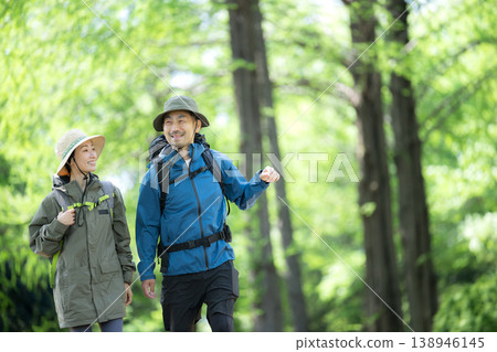 An outdoor scene of a couple walking through a forest, evoking images of activities like mountain climbing and trekking. An outdoor scene of a couple walking through a forest, evoking images of activities like mountain climbing and trekking. 138946145
