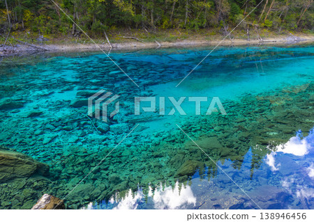 Fantastic view of the Five Colored Pool (the Colorful Pond) with azure crystal clear water among fall woods and evergreen forest in Jiuzhai Valley National Park in China. Fantastic view of the Five Colored Pool (the Colorful Pond) with azure crystal clear water among fall woods and evergreen forest in Jiuzhai Valley National Park in China. 138946456