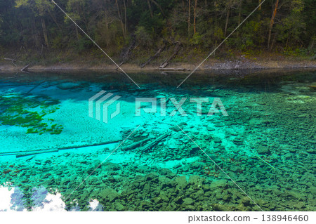 Fantastic view of the Five Colored Pool (the Colorful Pond) with azure crystal clear water among fall woods and evergreen forest in Jiuzhai Valley National Park in China. Fantastic view of the Five Colored Pool (the Colorful Pond) with azure crystal clear water among fall woods and evergreen forest in Jiuzhai Valley National Park in China. 138946460