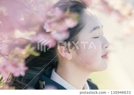 A female student gazes into the distance against a backdrop of cherry blossom trees. Spring portrait. Beauty image. A female student gazes into the distance against a backdrop of cherry blossom trees. Spring portrait. Beauty image. 138946633