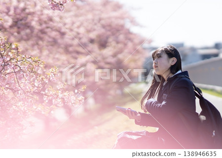 A portrait of a high school girl sitting on a riverbank after school, surrounded by cherry blossoms. (Keywords: beautiful skin, skincare, springtime youth) A portrait of a high school girl sitting on a riverbank after school, surrounded by cherry blossoms. (Keywords: beautiful skin, skincare, springtime youth) 138946635