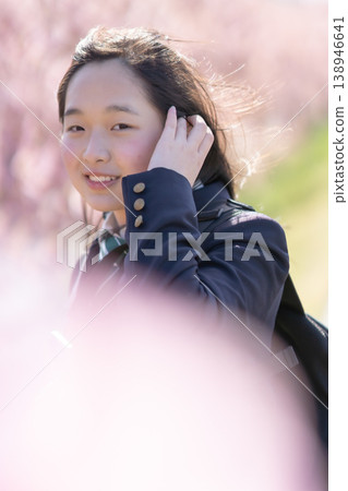 A portrait of a female student walking to school under cherry blossoms, wearing a blazer. A portrait of a female student walking to school under cherry blossoms, wearing a blazer. 138946641