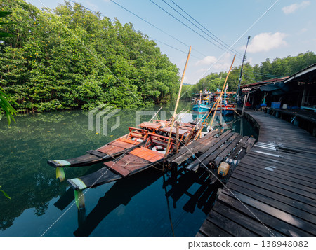 Traditional wooden boats moored in a calm green river surrounded by lush mangrove forest. Traditional wooden boats moored in a calm green river surrounded by lush mangrove forest. 138948082
