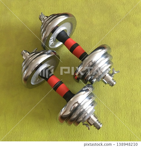 Weights sit on a bright green surface ready for a workout session in a home gym 138948210