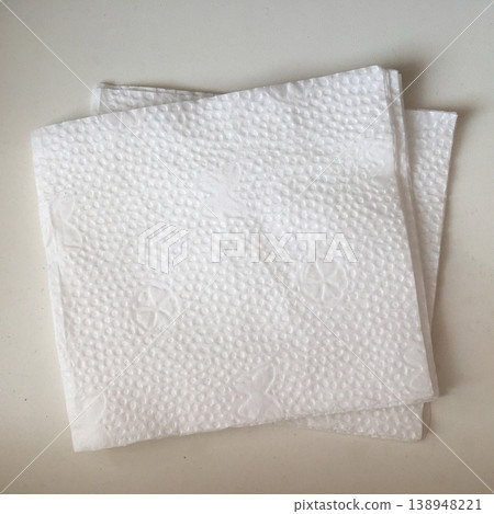 Stack of white paper napkins placed on a flat surface showing a simple design and texture during midday Stack of white paper napkins placed on a flat surface showing a simple design and texture during midday 138948221