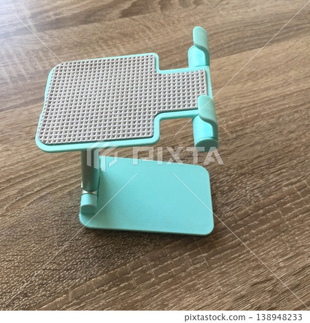 Stand for tablet or phone on wooden surface in bright light for home or office use Stand for tablet or phone on wooden surface in bright light for home or office use 138948233