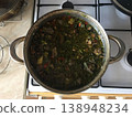 Cooking a traditional dish in a pot on a stove with fresh ingredients in a kitchen setting during the day 138948234