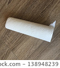 Roll of paper towels placed on wooden floor in kitchen used for cleaning spills and messes during daily chores or cooking tasks 138948239