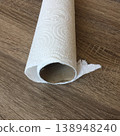 Used paper towel roll on wooden surface after cleaning small spills or messes in kitchen or dining area during daytime hours 138948240