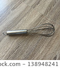 Metal whisk on a wooden surface in a kitchen setting during daylight 138948241