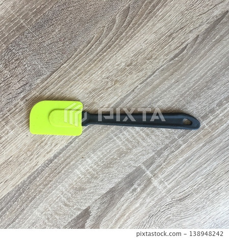 Bright silicone spatula rests on wooden kitchen surface near cooking area while preparing food during daytime in a home setting Bright silicone spatula rests on wooden kitchen surface near cooking area while preparing food during daytime in a home setting 138948242