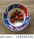 Fresh strawberries are placed in a decorative bowl with colorful patterns on a wooden table 138948246