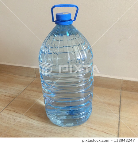 Clear plastic water bottle on a wooden floor in a bright indoor space during the day Clear plastic water bottle on a wooden floor in a bright indoor space during the day 138948247