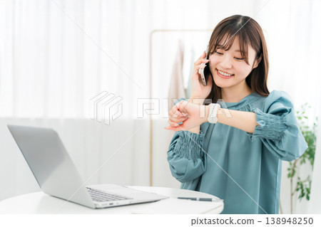一位時尚的年輕亞洲女性一邊使用電腦,一邊用智慧型手機通話 一位時尚的年輕亞洲女性一邊使用電腦,一邊用智慧型手機通話 138948250