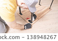 A worker in special clothes collects furniture in close-up. Assembling a new table by the wizard 138948267