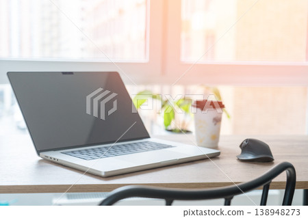 Laptop on the desk indoors, daylight from the window, coffee cup, mouse on the desk, workspace in a modern businessman. 138948273