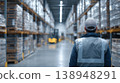 Worker observes warehouse operations in industrial storage area during daytime shift hours 138948291