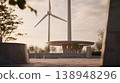 Wind turbines stand in a public space surrounded by trees and benches at sunset in a quiet area 138948296