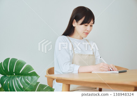 A woman is taking notes on the menu; a scene depicting meal preparation and daily planning. 138948324