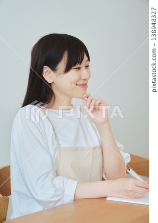 A woman is taking notes on the menu; a scene depicting meal preparation and daily planning. A woman is taking notes on the menu; a scene depicting meal preparation and daily planning. 138948327