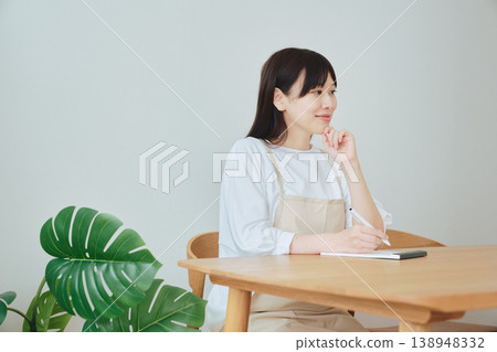 A woman is taking notes on the menu; a scene depicting meal preparation and daily planning. A woman is taking notes on the menu; a scene depicting meal preparation and daily planning. 138948332