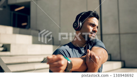 Fitness, headphones and man stretching arms on stairs in city, workout and exercise for body health. Music, serious athlete and person warm up on steps in urban town, listening to audio and thinking 138948692
