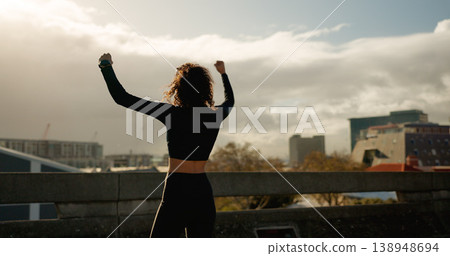 Woman, freedom and winning in city for fitness achievement, workout or outdoor training success. Rear view of female person, runner or athlete in celebration for goals or victory in an urban town Woman, freedom and winning in city for fitness achievement, workout or outdoor training success. Rear view of female person, runner or athlete in celebration for goals or victory in an urban town 138948694