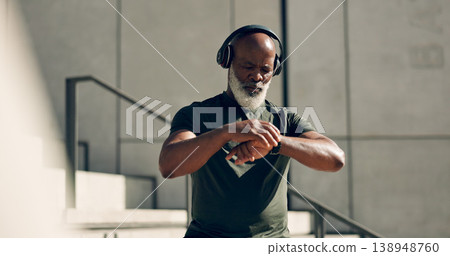 Fitness, headphones and black man on smart watch in city, workout progress and exercise results for body health. Music, senior athlete and check time on clock, heart rate and serious in town on steps 138948760