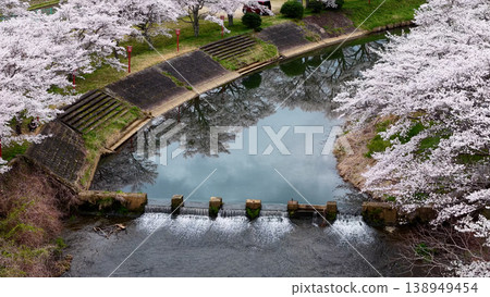 Cherry blossoms in full bloom reach the water's surface, creating a refreshing spring scene along the river. Cherry blossoms in full bloom reach the water's surface, creating a refreshing spring scene along the river. 138949454